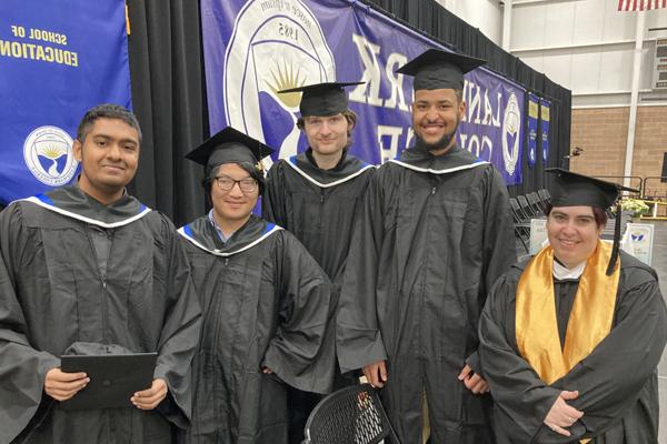 12月17日的毕业典礼前，五名学生站在毕业舞台上，戴着帽子和长袍摆姿势拍照